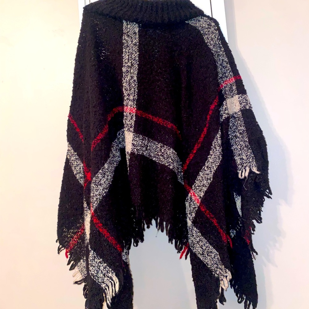 A rolled turtleneck accents the relaxed fit while fringe tassels finish